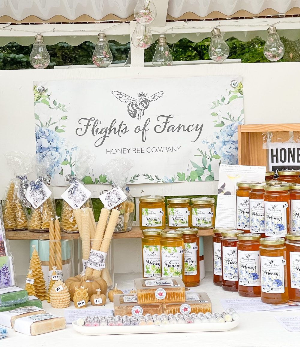 Their farm stand, with linden and wildflower honey, cut comb, beeswax candles and soaps under a Flights of Fancy sign.